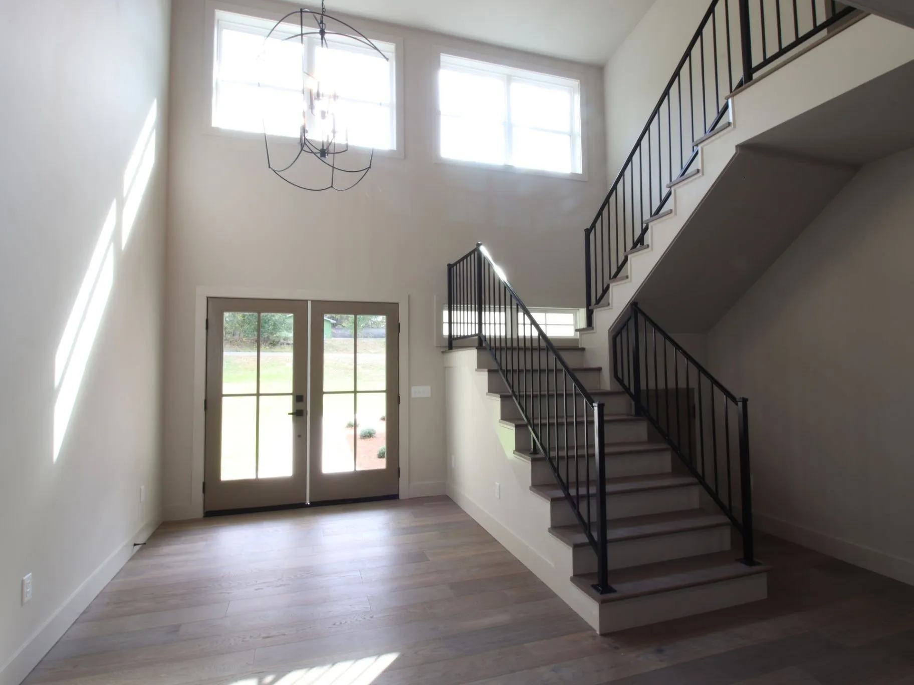 Completed JC T1 foyer with a double-height ceiling, chandelier, front doors, and staircase