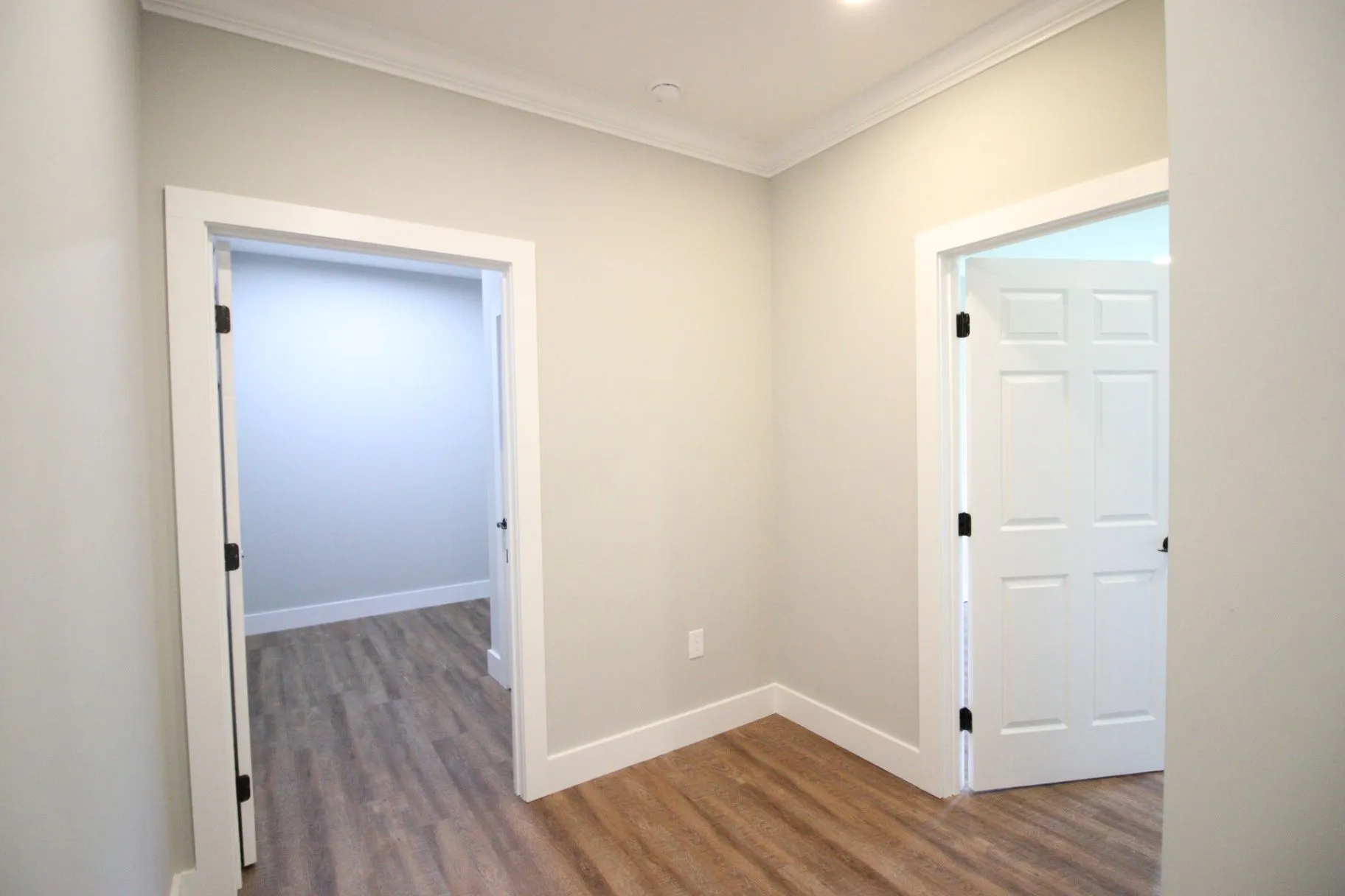 Completed JP2 New Construction interior room with finished flooring, trim, and an open doorway