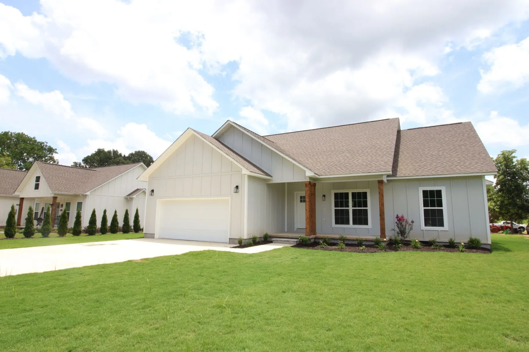 Completed JP2 New Construction home with white siding, gabled rooflines, and a broad front lawn