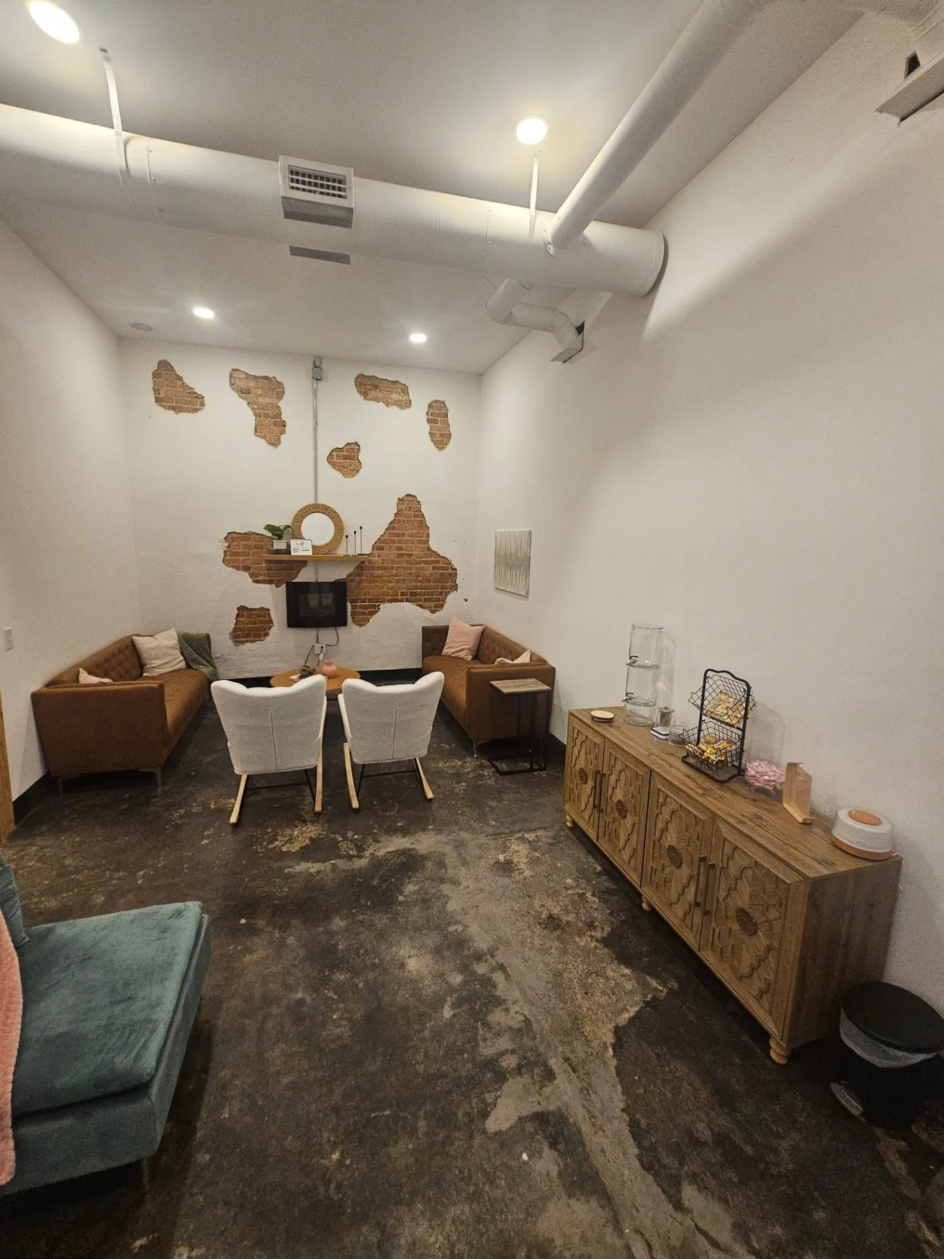 Completed spa lounge with leather seating, exposed brick, and a carved wood console