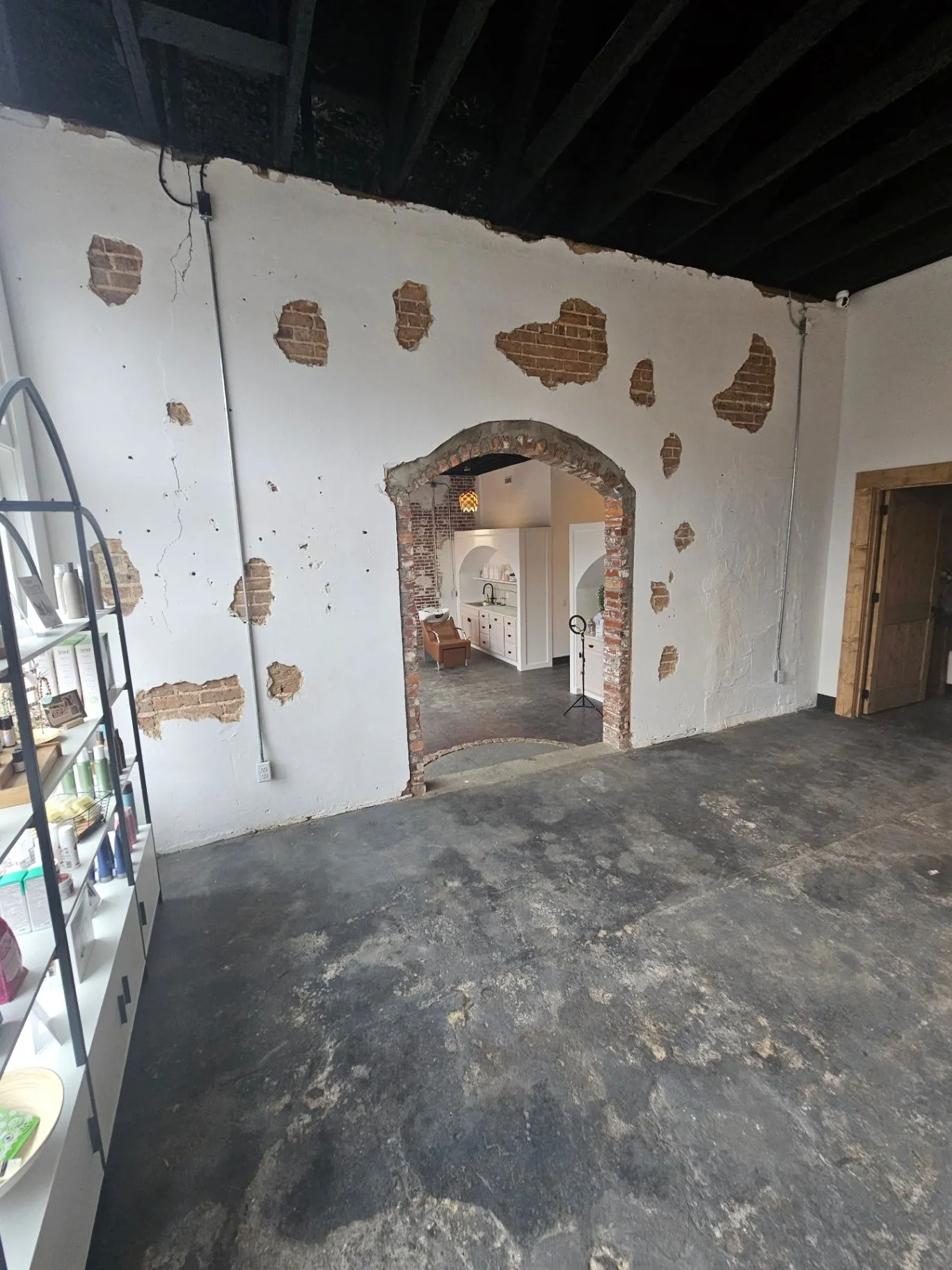 Completed spa room with an exposed brick archway, dark ceiling, and retail shelving