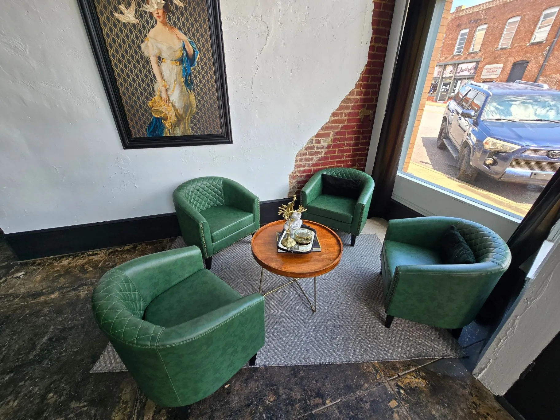 Completed Wine Bar lounge with green chairs, a round wood table, and framed art