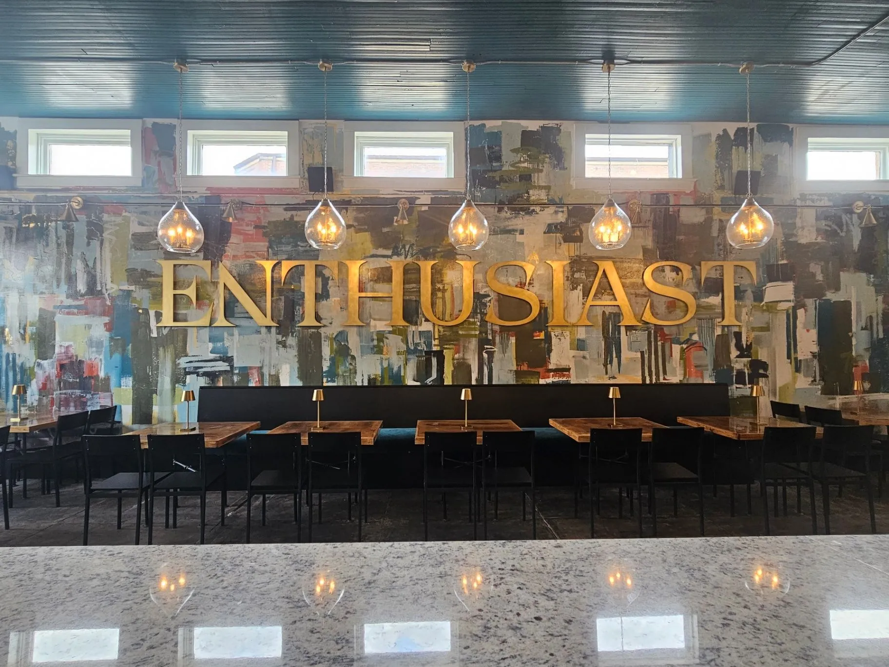 Completed Wine Bar dining room with a colorful mural, pendant lights, and wood tables